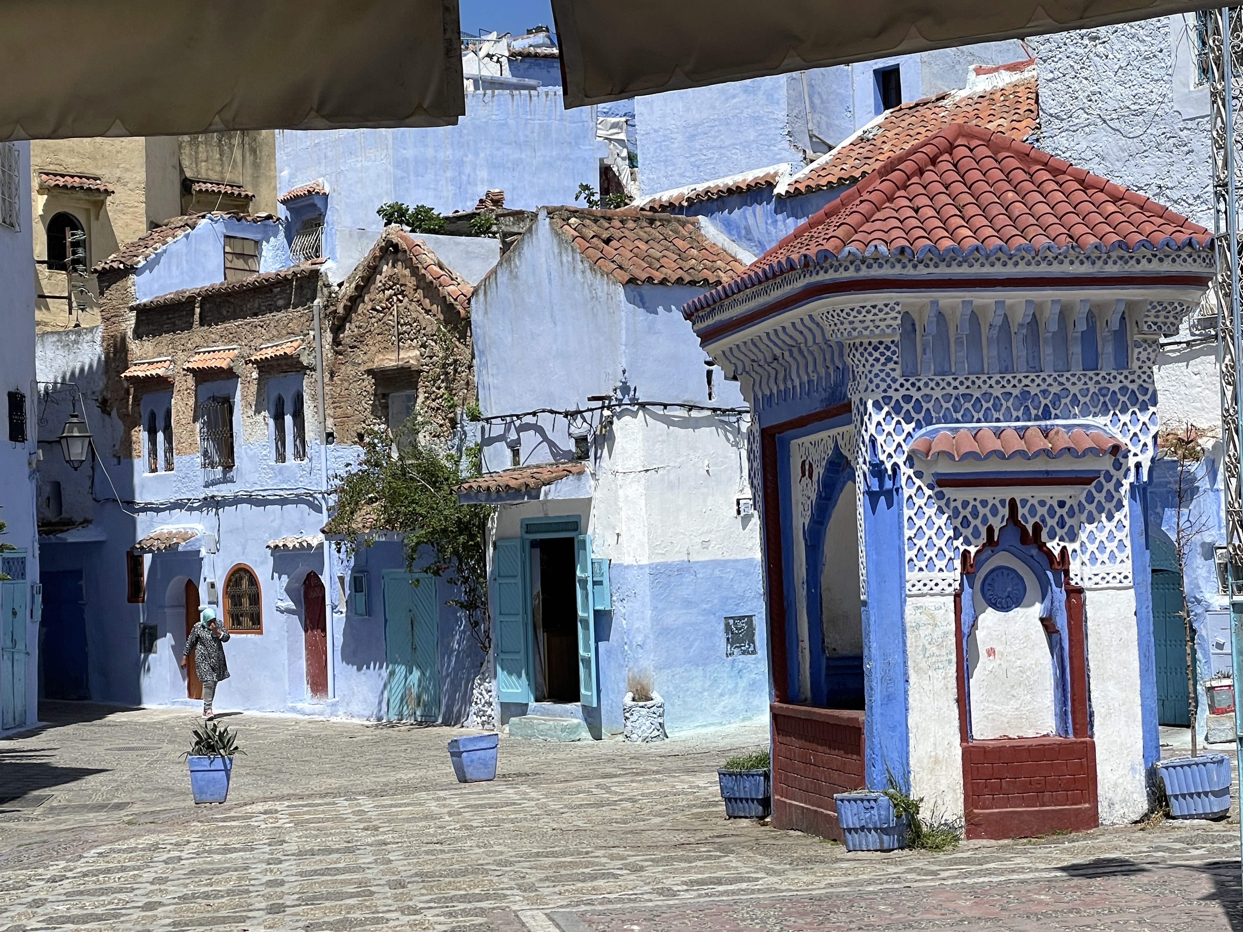 Blau-weiße Häuser und ein verzierter Brunnen auf einem Platz in Chefchaouen